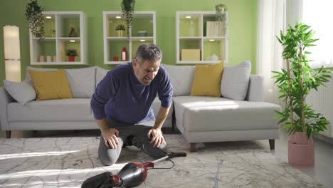 Old-man-cleaning-at-home,-using-vacuum-cleaner-to-clean-carpet-and-floor-in-living-room.